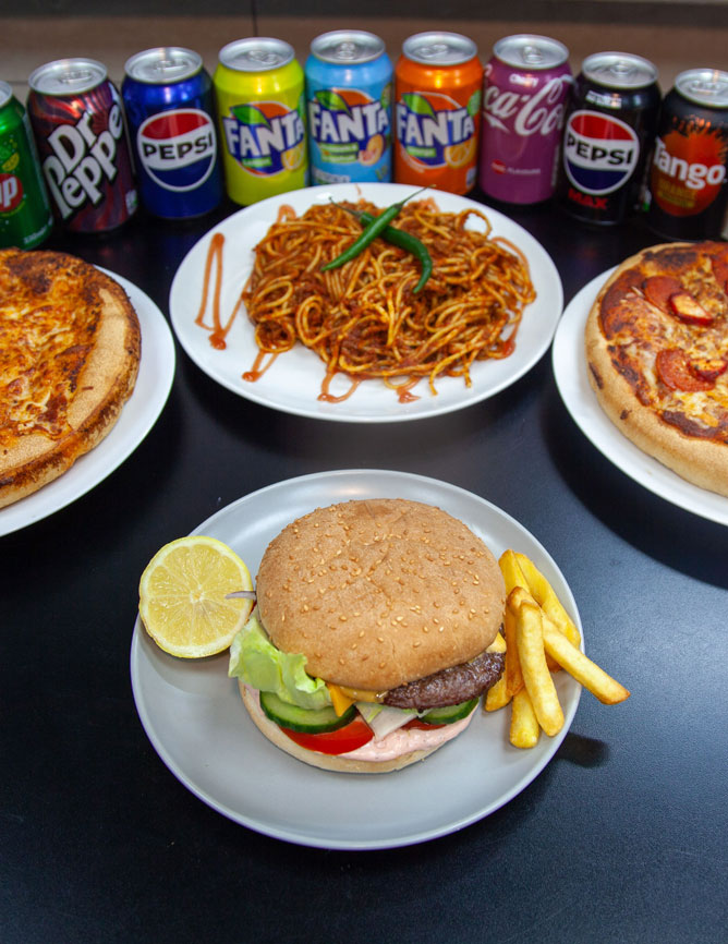Mama Mia in Birmingham pizzas, spaghetti, burgers, fries, and soda cans on a black table.